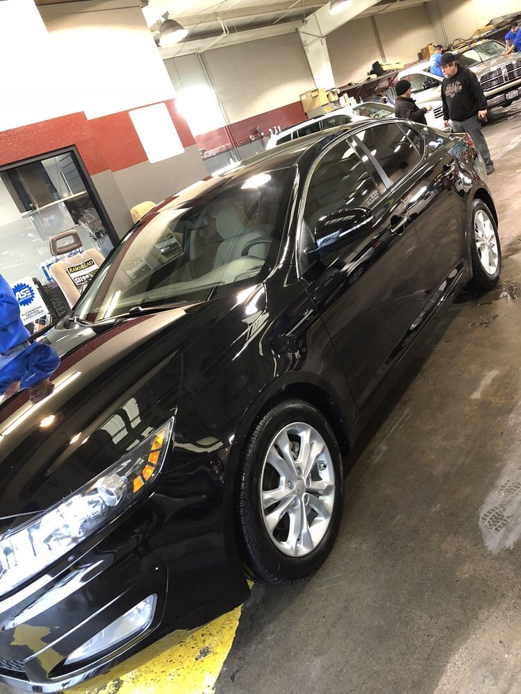 Black sedan being detailed inside the wash bay